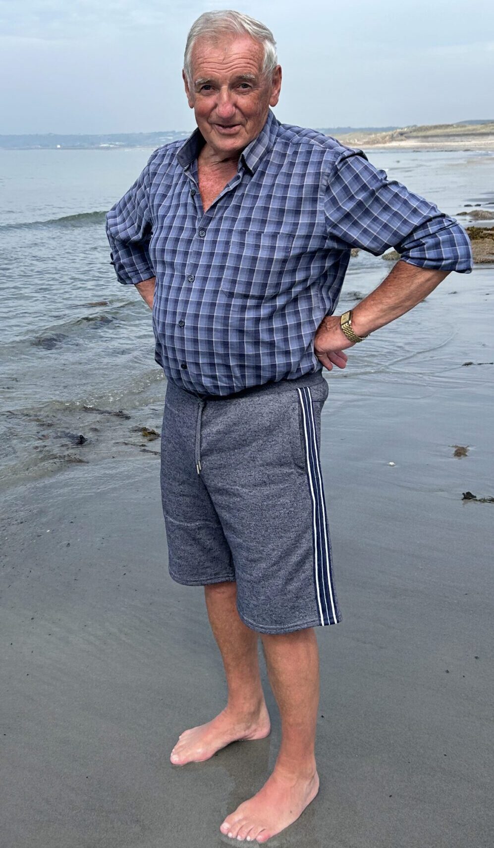Man standing barefoot on the beach.