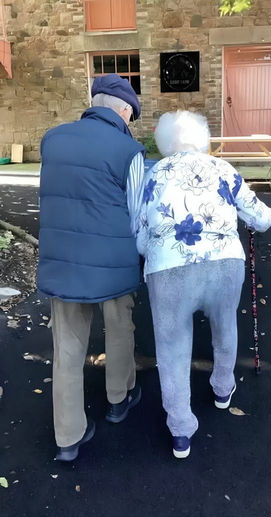 Elderly couple walking together outside building.