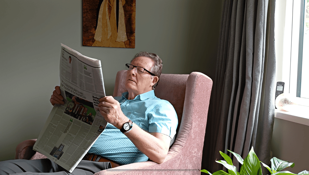 Man reading newspaper in a cozy chair.